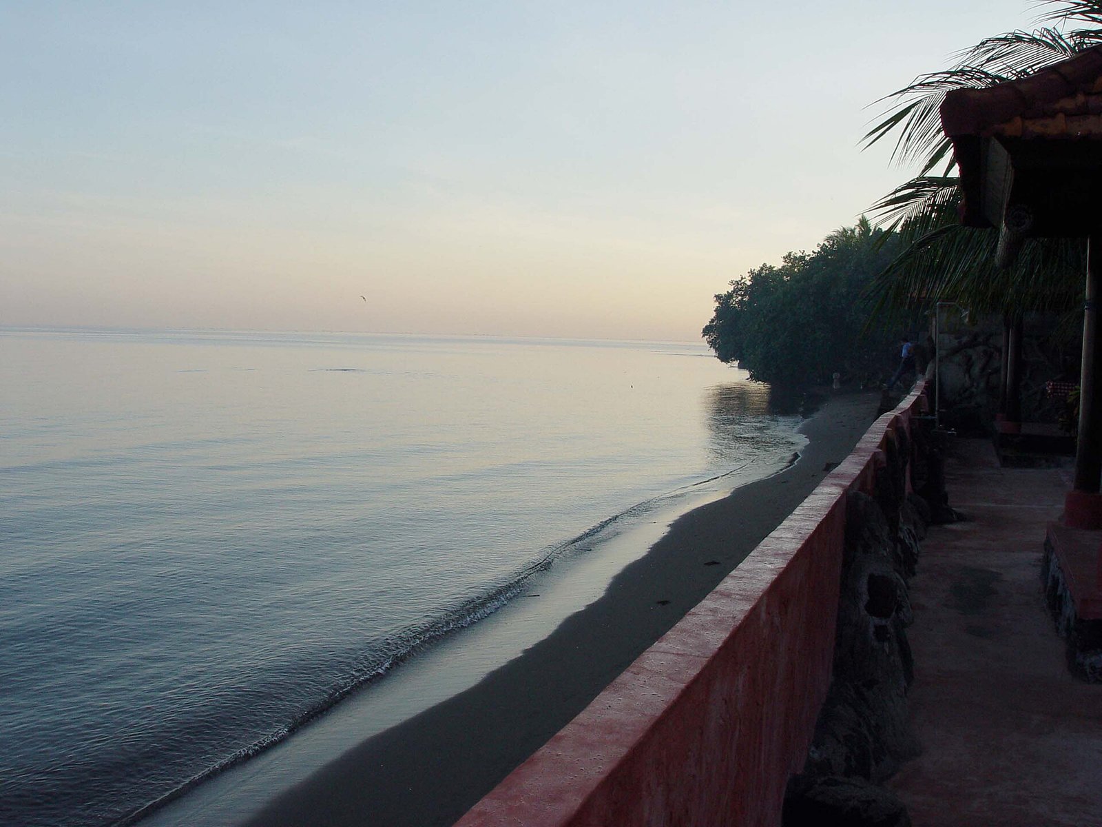 Calm morning sea and dark volcanic sand at Lovina Beach, north Bali