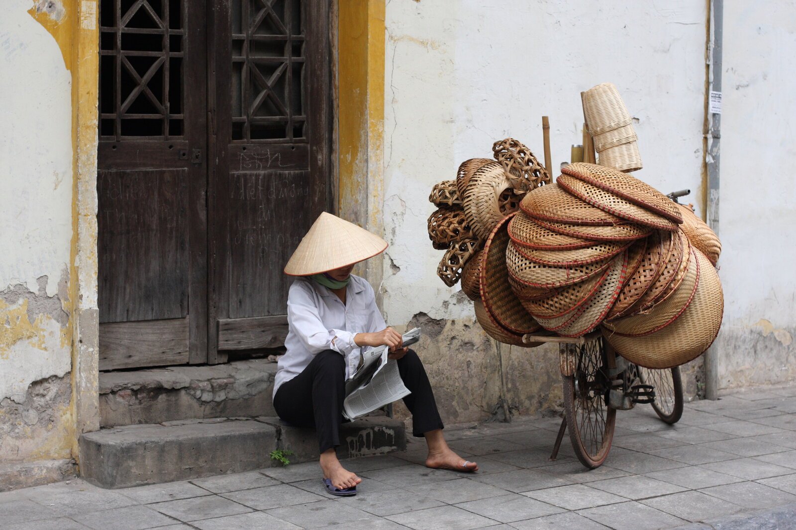 Narrow street with vendors and motorbikes in Hanoi's Old Quarter, Vietnam