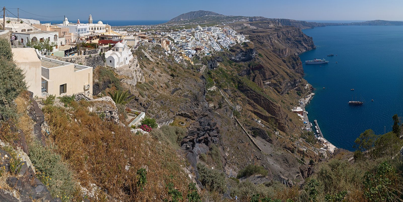 The village Fira on the volcanic island Santorini in Greece. The road leading to the old port where cruise ships anchor can also be seen. Pa — Photo: Christian Mehlführer, User:Chmehl, CC BY 2.5, via Wikimedia Commons