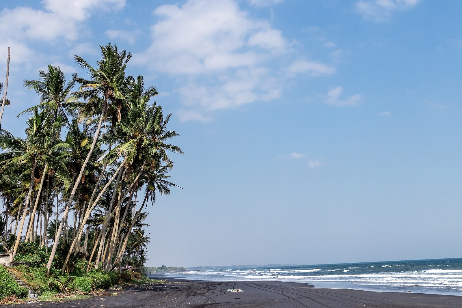 Landscape of black sand beach with beautiful palms. Bali island. Indonesia. — Photo: Artem Beliaikin from Moscow, Russia, CC0, via Wikimedia Commons