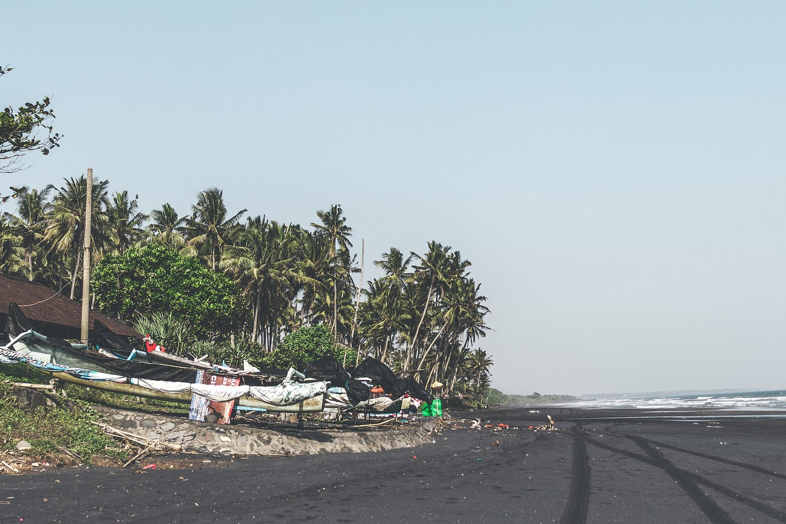 Landscape of black sand beach with beautiful palms. Bali island. Indonesia. — Photo: Artem Beliaikin from Moscow, Russia, CC0, via Wikimedia Commons