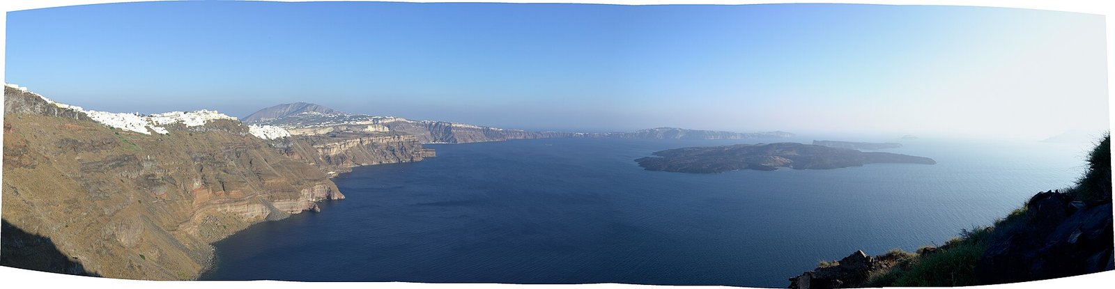 Santorini caldera panorama, shot from North to South, as seen from from Skaros rock formation, showing Nea Kameni and Palea Kameni volcanic  — Photo: Yanko Malinov, CC BY-SA 4.0, via Wikimedia Commons